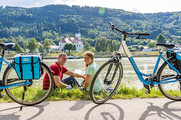 Zwei Radler bei einer Pause am Ufer der Donau gegenüber von Engelszell.