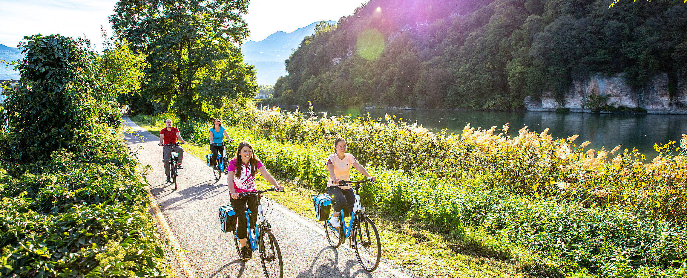 Vier Radler auf dem Etschradweg bei Rovereto im Sommer.