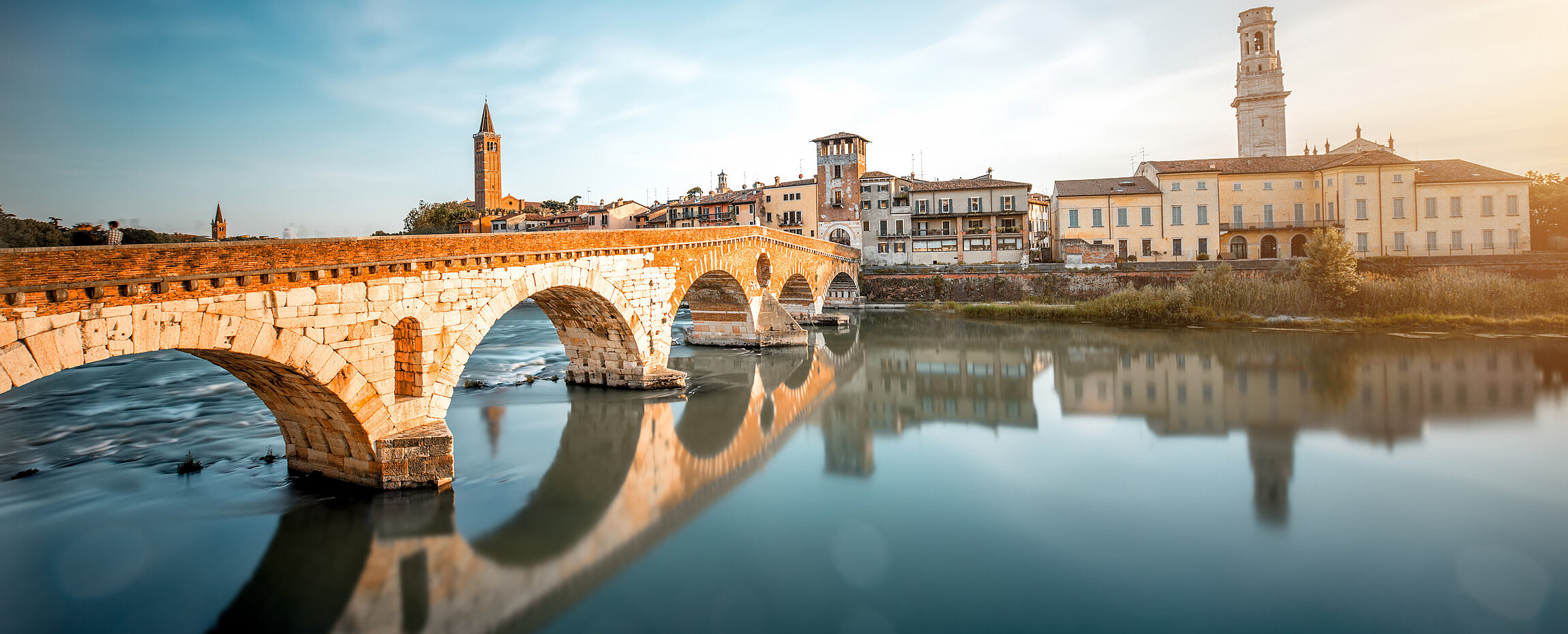 Blick auf die Ponte Pietra über die Etsch in Verona, mit der Altstadt im Hintergrund.