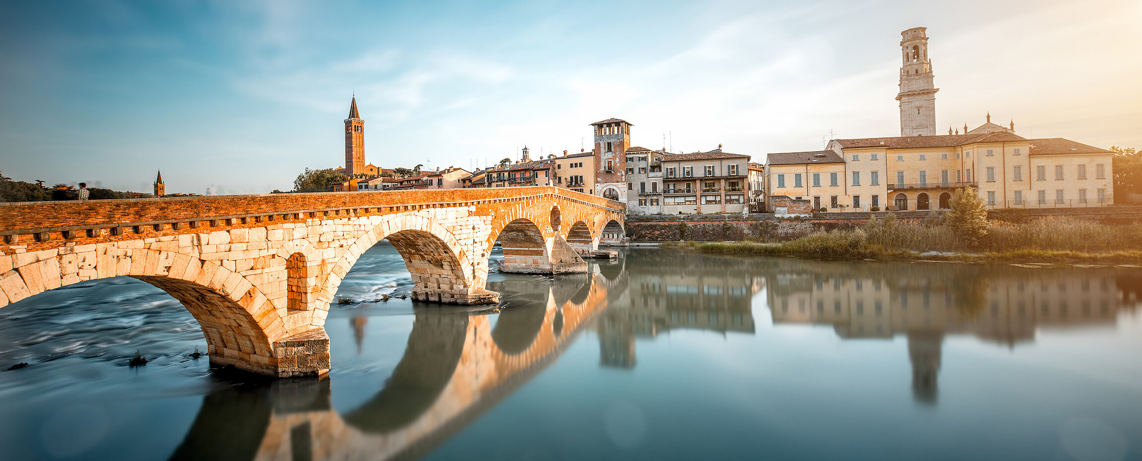 Blick auf die Ponte Pietra über die Etsch in Verona, mit der Altstadt im Hintergrund.